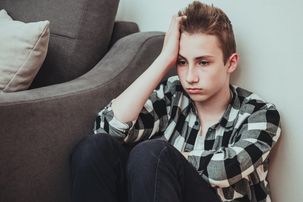 Sad teen boy sit on the floor thinking of her trouble and unhappy life and close his ears