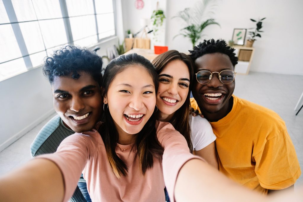 Young group of happy multiracial friends taking selfie portrait at home