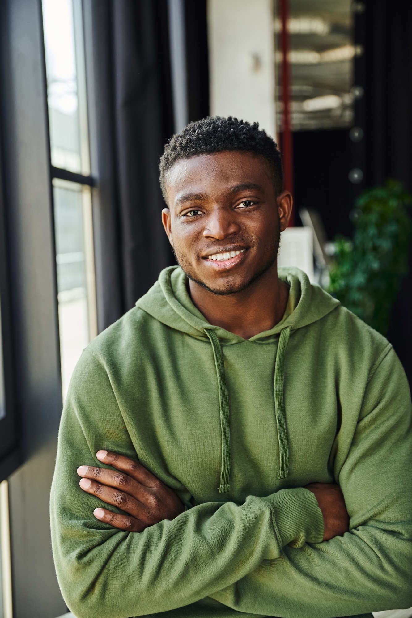 youthful and charismatic african american entrepreneur in green and trendy hoodie standing